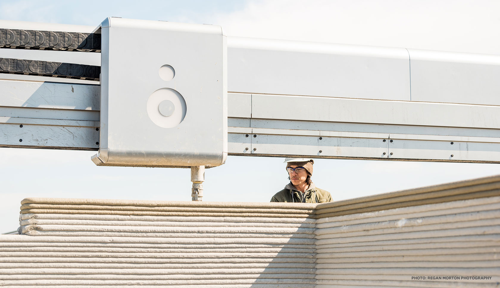 construction worker monitoring a vulcan 2 as it prints a home