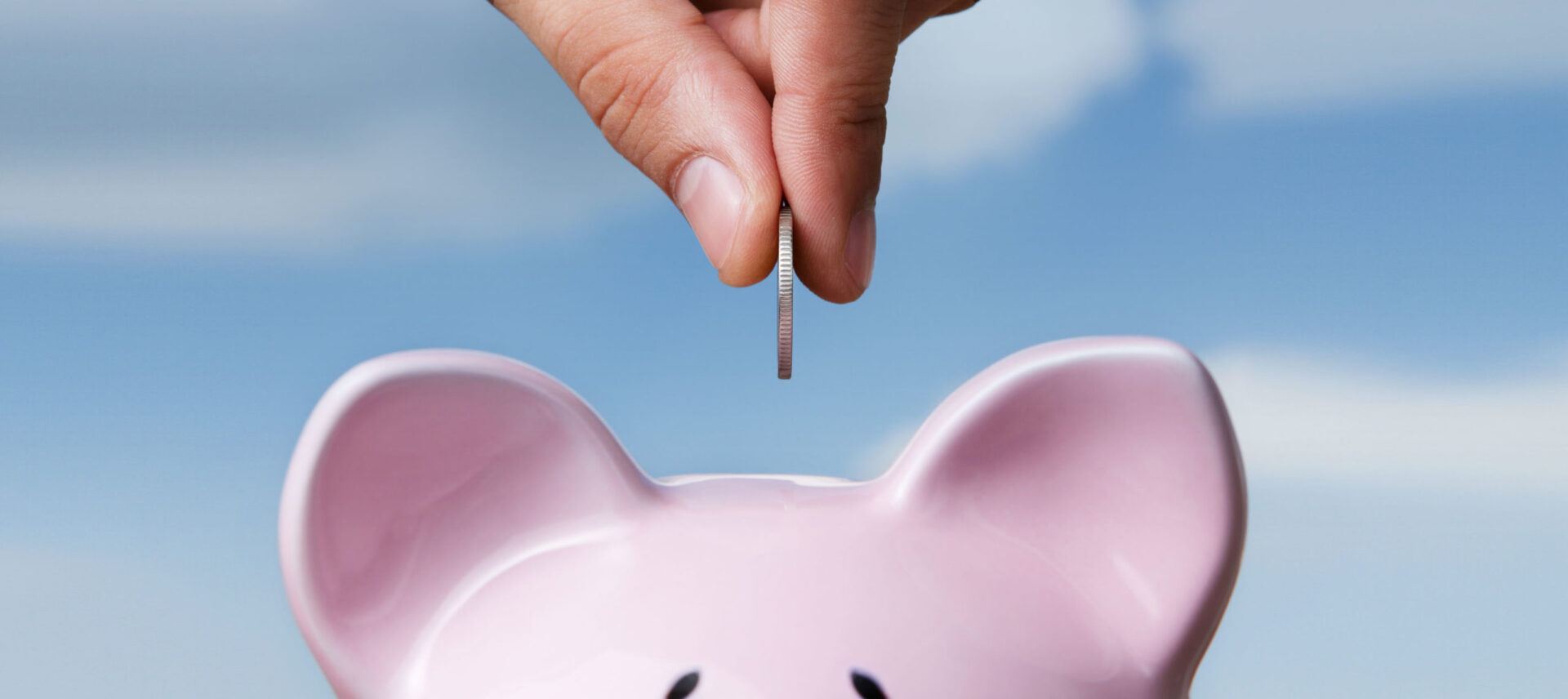 hand putting coins in piggy bank