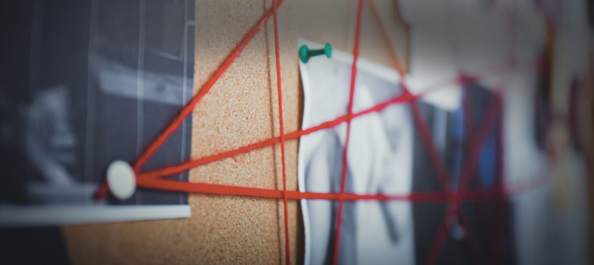 red yarn linking items on a cork board