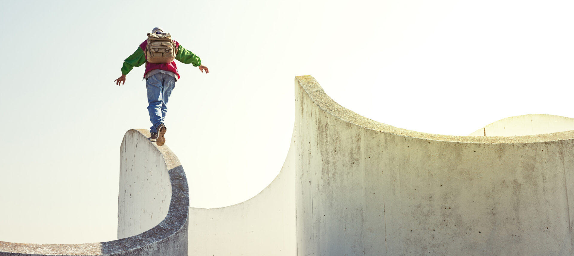 man walking on the edge of a concrete wall