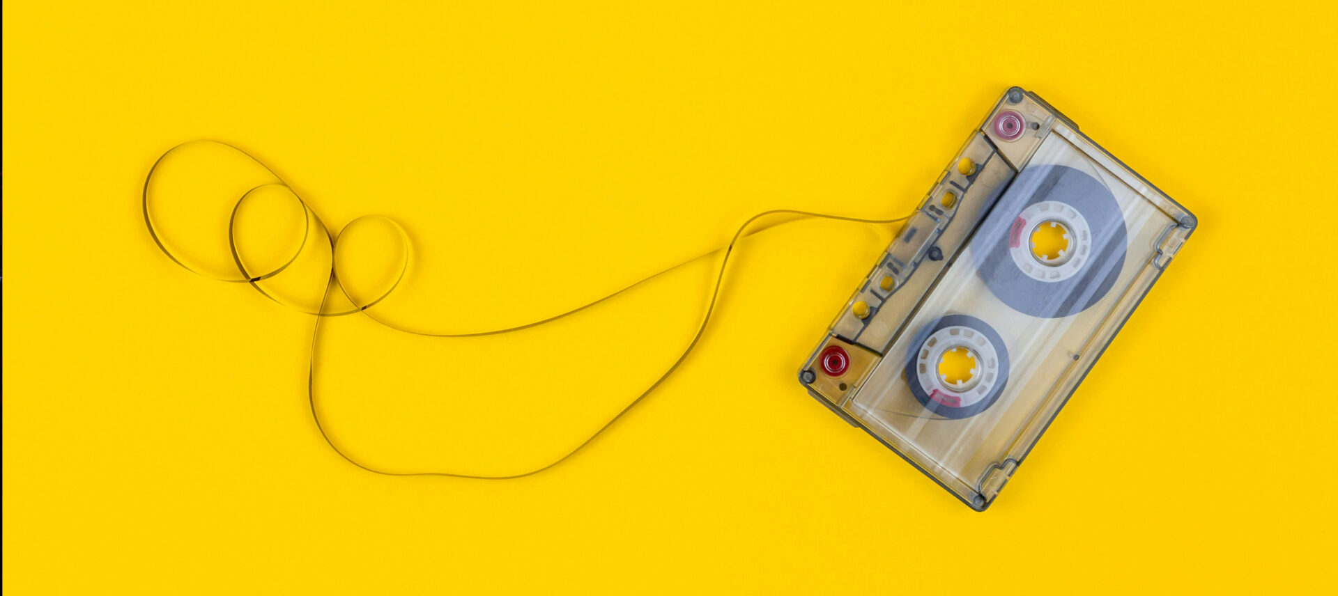 Cassette tape pulled out of case on yellow background